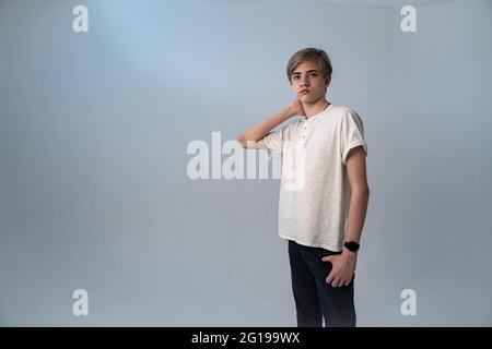 Bel adolescente si trova su uno sfondo grigio-blu. Primo piano ritratto in studio di giovane caucasico Foto Stock