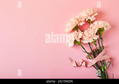 Bouquet di garofani rosa. Design concetto di saluto di vacanza con bouquet di garofano su sfondo rosa tavolo. Foto Stock