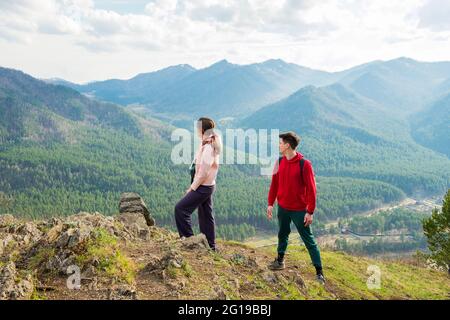 Una giovane coppia di viaggiatori si trova sulla cima della montagna. Uomo e donna trekking con zaini su un bellissimo sentiero roccioso. Viaggi locali per famiglie e. Foto Stock