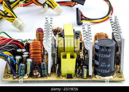 Un'alimentazione del computer aperta a 220 volt con componenti elettronici visibili sulla scheda a circuito stampato. Foto Stock