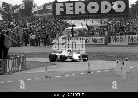 John Watson porta la McLaren MP4 ai box durante le prove libere per il Gran Premio di Silverstone 1981. Foto Stock