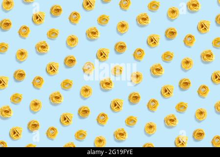Pop art sfondo dalle tagliatelle di pasta italiana. Pasta cruda fettuccine pop art sfondo, piatto. Pasta italiana al nido crudo isolata in blu Foto Stock