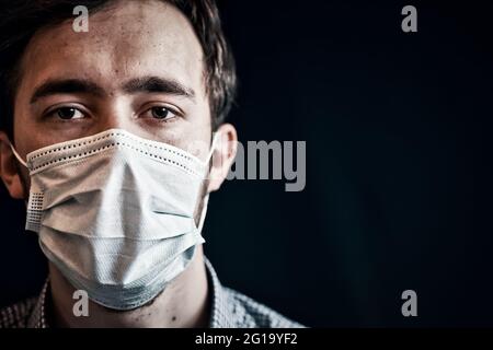Uomo in maschera. Uomo che indossa una maschera igienica per prevenire le infezioni con una vista malata drammatica Foto Stock