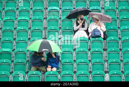 I fan si rifugiano sotto gli ombrelloni durante una pausa pioggia durante il secondo giorno del Viking Open al Nottingham Tennis Center. Data immagine: Domenica 6 giugno 2021. Foto Stock