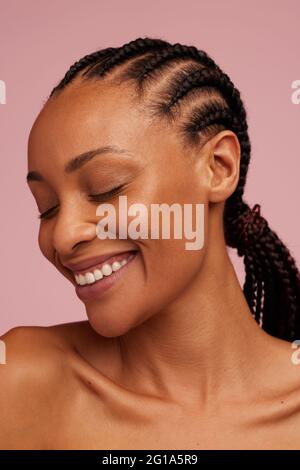 Primo piano di bella donna su sfondo rosa. Affascinante donna africana faccia con bella pelle. Foto Stock