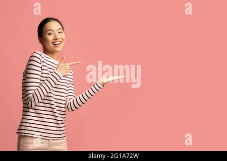 Guardate questo. Positivo giovane Asian femmina che punta alla sua palma aperta Foto Stock