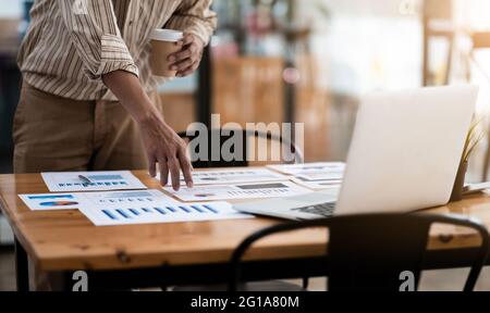 Uomo d'affari che discute le tabelle o i grafici di analisi sul tavolo da tavolo e usando il computer portatile.Chiudi l'analisi maschile e il concetto di strategia. Foto Stock