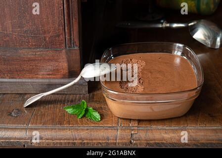 Ciotola trasparente con mousse al cioccolato francese tradizionale su una vecchia sponda in legno Foto Stock