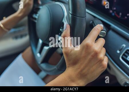 La mano della donna commuta i lobi del selettore del cambio sul volante. La mano sta cambiando la leva del cambio dell'auto, primo piano di un cambio marcia manuale Foto Stock