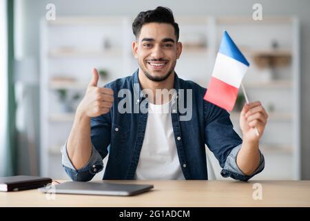 Ragazzo sorridente con bandiera della Francia e mostrando il pollice in su Foto Stock