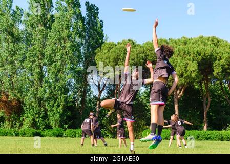 Gruppo di giovani adolescenti in squadra indossare giocare una partita di frisbee nel parco oudoors. Salto uomo prendere un frisbee a un compagno di squadra in un frisbee finale Foto Stock