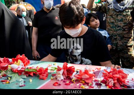 (6/6/2021) un ragazzo iraniano che indossa una T-shirt con un ritratto dell'ex corpo della Guardia rivoluzionaria islamica iraniana (IRGC), il generale Qasem Soleimani della Quds Force, ucciso in un attacco di droni americani nell'aeroporto di Baghdad, e si trova dietro una bara beffata con bandiera di un soldato sconosciuto ucciso nel 1980-88 Guerra Iran-Iraq e i cui resti sono stati recentemente recuperati nei campi di battaglia. (Foto di Sobhan Farajvan / Pacific Press/Sipa USA) Foto Stock