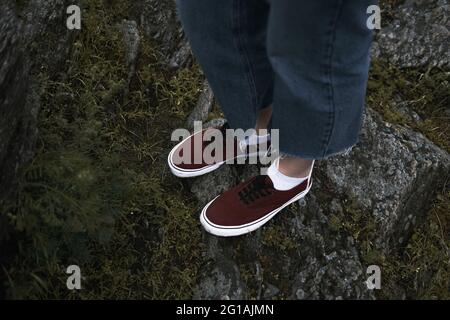 Scarpe di colore rosso scuro sulle rocce, camminando all'aperto nella natura Foto Stock