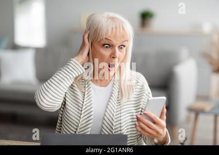 Sorpresa scioccata donna matura utilizzando il telefono cellulare Foto Stock