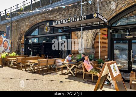 Persone che siedono fuori Battersea Brewery una micro birreria e bar nel Circus West Village parte della nuova rigenerazione della Battersea Power Station, Londra Foto Stock