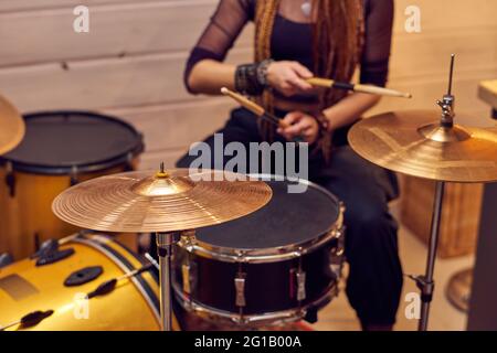 Drum set e giovane femmina con i drumsticks seduti vicino Foto Stock