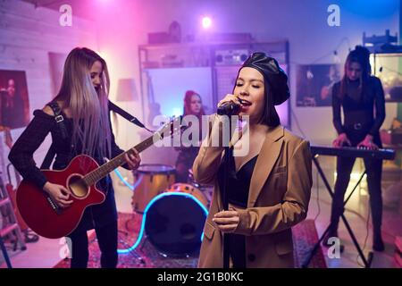 Giovane donna affascinante che canta nel microfono sul palco Foto Stock