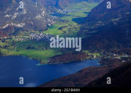 Vista sul lago di Bohinj, sulla chiesa e sul villaggio di Stara Fuzina in autunno, vista dalla stazione sciistica del Monte Vogel, dal Parco Nazionale del Triglav, Slovenia. Foto Stock