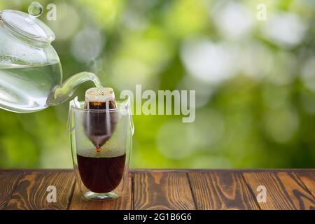 versare il caffè a mano in vetro su un tavolo di legno Foto Stock