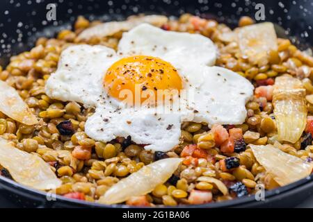 lenticchie con carne affumicata e cipolla servite con uova fritte Foto Stock