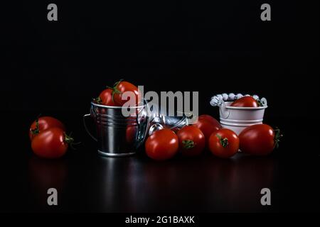 Una composizione con mini secchi decorativi e pomodori ciliegini Foto Stock