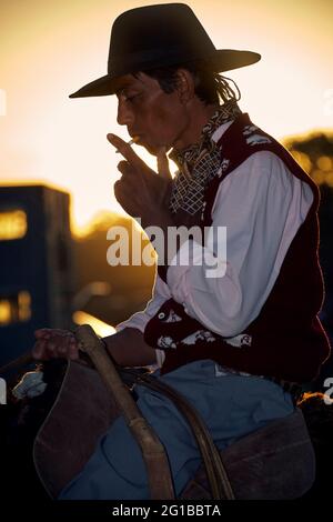 Gaucho fuma un cigarrette sopra il suo cavallo. San Antonio de Areco, Buenos Aires, Argentina. Foto Stock