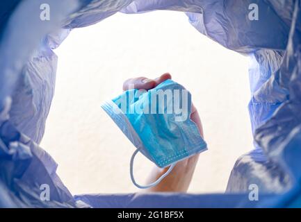 Gettare una maschera nel cestino. Con una vista dall'interno della spazzatura bin.Post pandemic cestino. Foto Stock