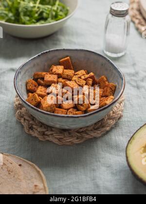 Dall'alto di cubetti di cagliata di fagioli fritti in ciotola a tavola con tortilla e sale tra ingredienti freschi Foto Stock