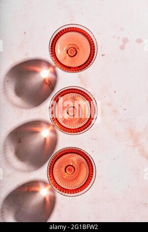 Vista dall'alto di un set di eleganti bicchieri con delizioso vino servito su un tavolo in marmo alla luce del sole Foto Stock