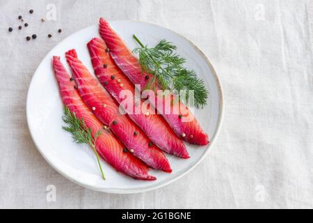 Da sopra gravlax con peppercorne miste e sprigg di aneto fresco su piatto su sfondo chiaro Foto Stock