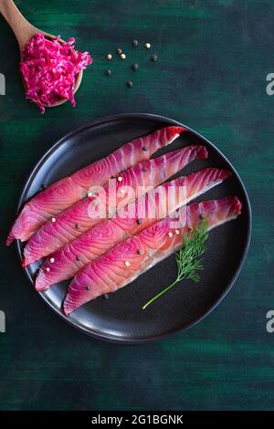 Da sopra gravlax con peppercorne miste e sprigg di aneto fresco su piatto su fondo scuro Foto Stock