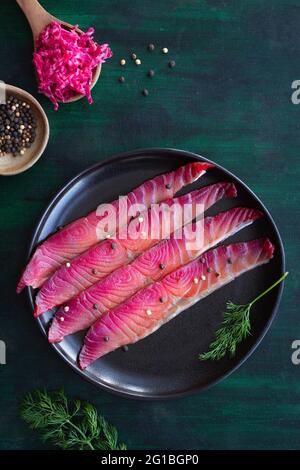 Da sopra gravlax con peppercorne miste e sprigg di aneto fresco su piatto su fondo scuro Foto Stock