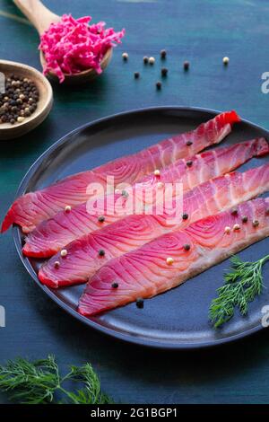 Da sopra gravlax con peppercorne miste e sprigg di aneto fresco su piatto su fondo scuro Foto Stock