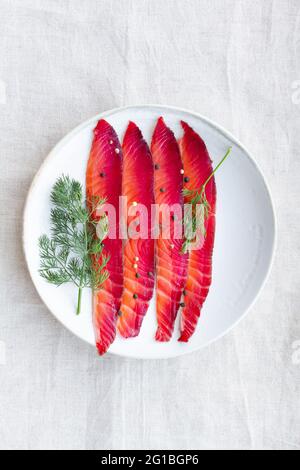 Da sopra gravlax con peppercorne miste e sprigg di aneto fresco su piatto su sfondo chiaro Foto Stock