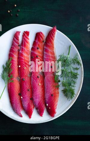 Da sopra gravlax con peppercorne miste e sprigg di aneto fresco su piatto su fondo scuro Foto Stock