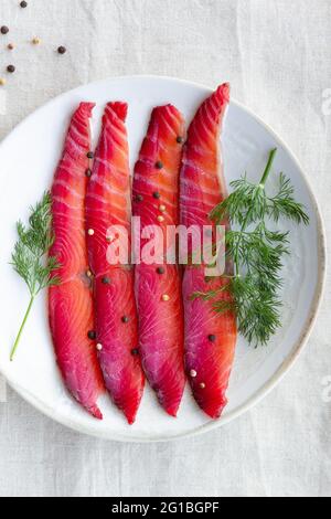 Da sopra gravlax con peppercorne miste e sprigg di aneto fresco su piatto su sfondo chiaro Foto Stock