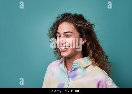 Giovane donna allegra che indossa una camicia estiva sorridente guardando via su sfondo blu Foto Stock