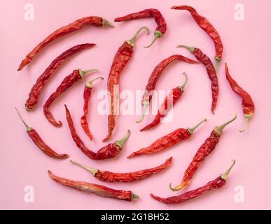 Piatto posare peperoncino rosso secco modello su uno sfondo di colore rosa. Vista dall'alto, disposizione piatta Foto Stock