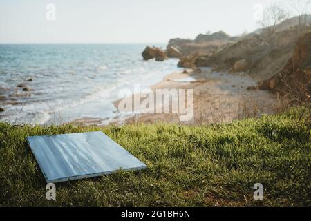 Dipinto posto sulla verde costa erbosa sopra il potente oceano con onde schiumose che lavano la spiaggia sabbiosa circondata da scogliere rocciose Foto Stock
