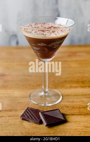Bicchiere di cocktail alcolico dolce fatto di latte liquoroso espresso e cioccolato posto su un tavolo di legno Foto Stock