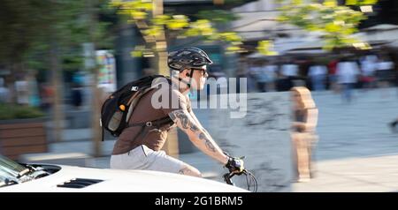 Belgrado, Serbia - 5 giugno 2021: Giovane uomo tatuato che cavalca una bicicletta sul traffico cittadino in una giornata di sole Foto Stock