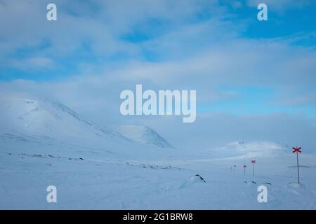 Racchette da neve Kungsleden Trail, lasciando Alesjaure cottage all'alba, Lapponia, Svezia, 2020 aprile. Le croci rosse segnano il sentiero. Foto Stock