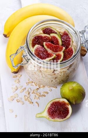 Old fashion di avena con yogurt greco banana e figure in un vaso bianco su sfondo rustico Foto Stock