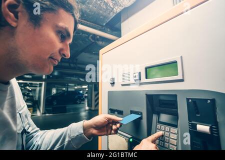 L'uomo paga per il parcheggio in una macchina speciale con carta di credito. Foto Stock