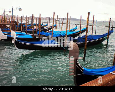 Molo con gondole a Venezia. Gondole ricoperte di teloni. Foto Stock