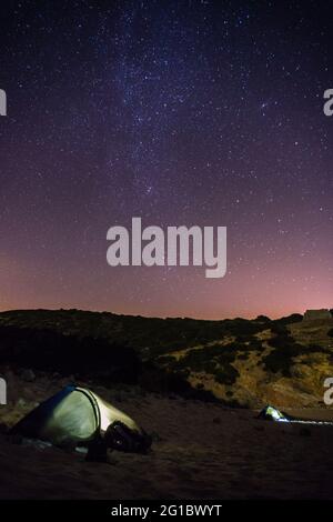 Due tende su una spiaggia di notte con modo lattiginoso sopra e roccia sullo sfondo, Figueira, Portogallo Foto Stock