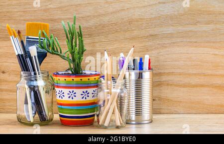 Vasetti riciclati, stagno e tazza riutilizzati per diversi contenuti su banco di legno Foto Stock