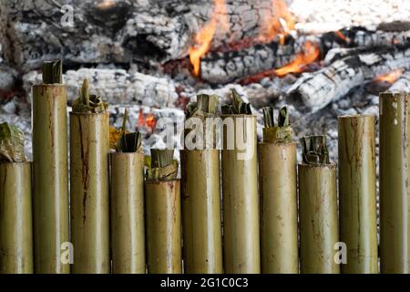 Una fila di lemang alla fine del processo di cottura. Lemang e' un cibo malese tradizionale di base durante il festival eid. Messa a fuoco selettiva. Sfondo sfocato Foto Stock