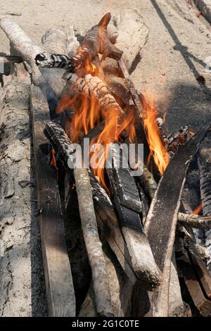 Primo piano di un mucchio di legna da ardere che brucia con fiamme arancioni e gialle. Punti di messa a fuoco selettivi. Sfondo sfocato Foto Stock
