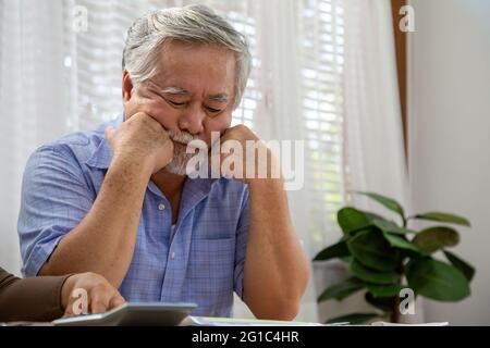 Uomo anziano asiatico che pensa a qualcosa e preoccupato o stress Foto Stock